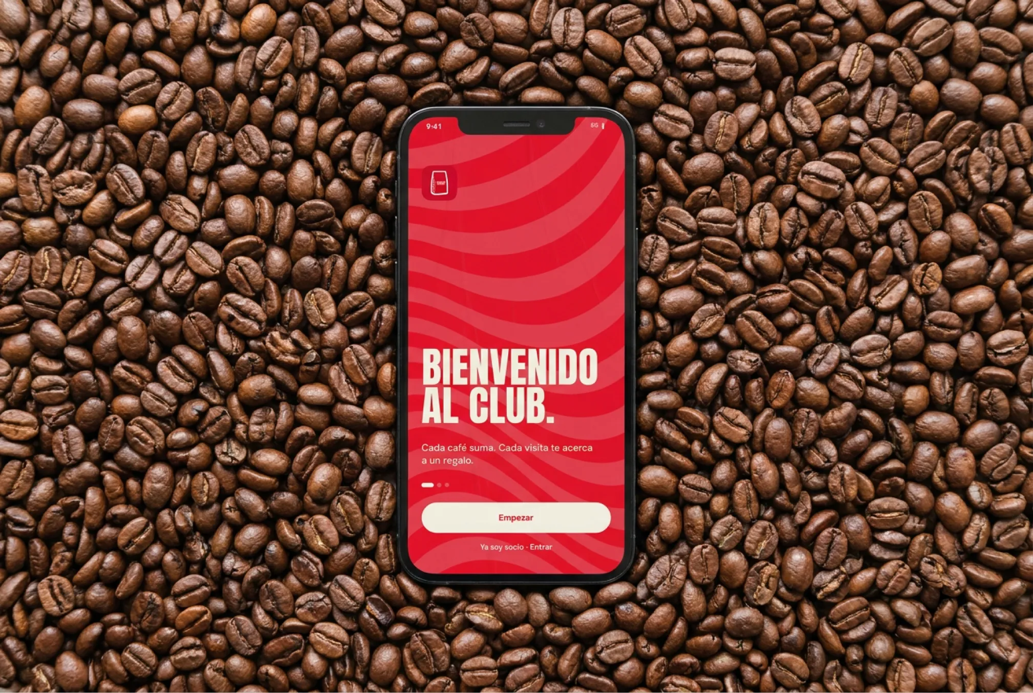 Visualización: móvil con la app El Club sobre granos de café tostado